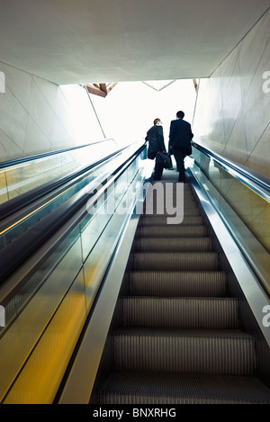 Businessmen riding escalator, rear view Stock Photo