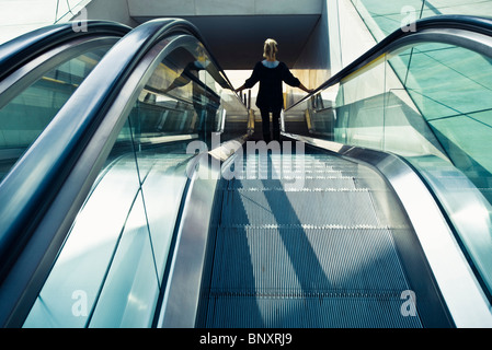 Riding escalator down, rear view Stock Photo