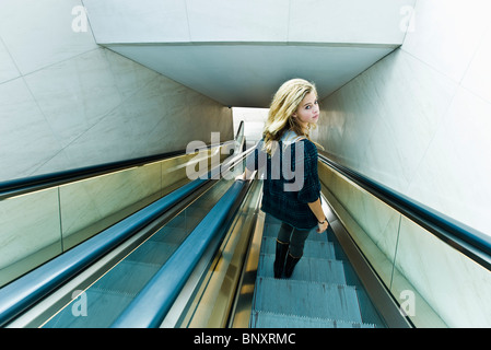 Teen girl riding escalator, looking over shoulder at camera Stock Photo