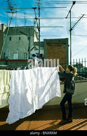 Teenage girl hanging laundry to dry on rooftop clothes-line Stock Photo