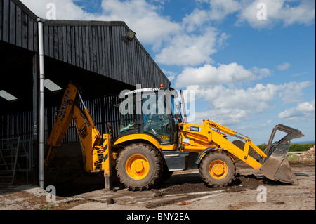 JCB 3CX digger preparing floor in an agricultural building Stock Photo