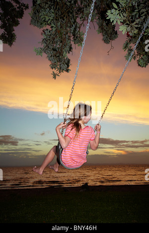 Young Girl on Rope Swing under Pohutukawa Tree at Sunset, Thames, Coromandel, North Island, New Zealand Stock Photo