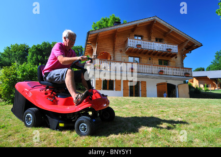 Lawnmower, Man driving a ride on lawn mower, cutting the grass with a ride on lawn mower Stock Photo