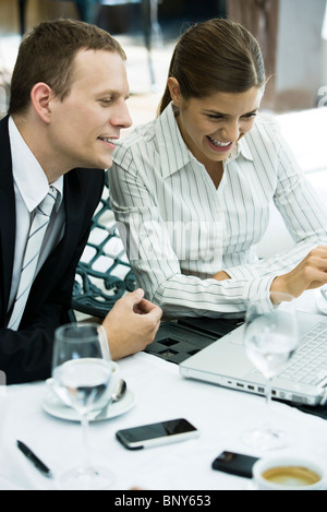 Business associates looking at laptop computer together in restaurant Stock Photo