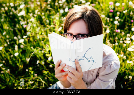 Woman hiding behind book Stock Photo
