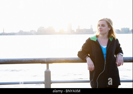 Woman leaning against a fence, with ipod Stock Photo