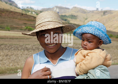 A smiling young Antemoro woman and a baby in raffia sunhats near Ambalavao, Haute Matsiatra, south-eastern Madagascar Stock Photo