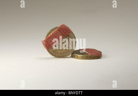 Two one pound coins with small plasters on a white background. Stock Photo