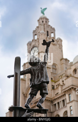 Statue of a boy with a toy plane in the Our lady and St Nicholas Church garden.  In the background is the Liver Building.  The statue comemerates Liverpudleans who died in the blitz.  Sculptor: Tom Murphy Stock Photo