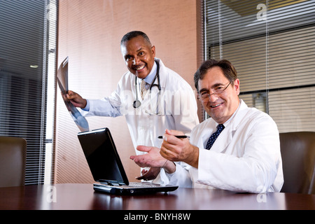 Happy doctors working in an office on laptop Stock Photo
