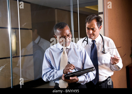 Multi-racial middle-aged doctors looking at tablet computer Stock Photo