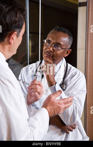 Two multiracial middle-aged doctors conversing Stock Photo