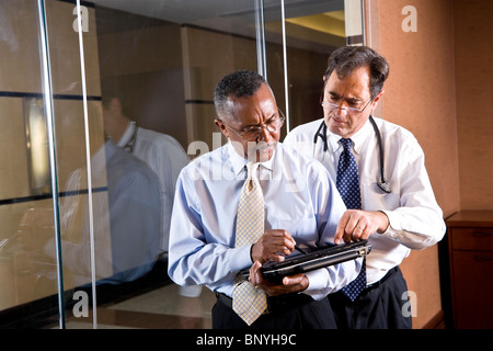 Multi-racial middle-aged doctors looking at tablet computer Stock Photo