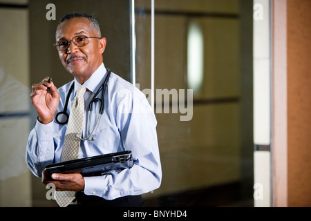 African American doctor writing notes on tablet computer Stock Photo