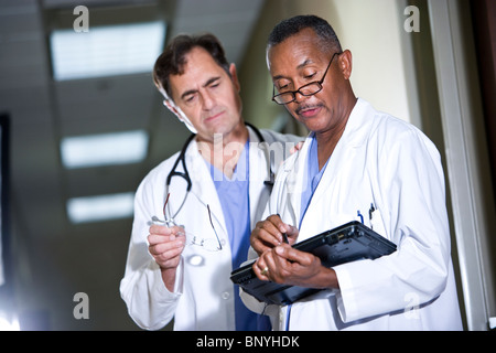 Two doctors reviewing notes on tablet computer in corridor Stock Photo
