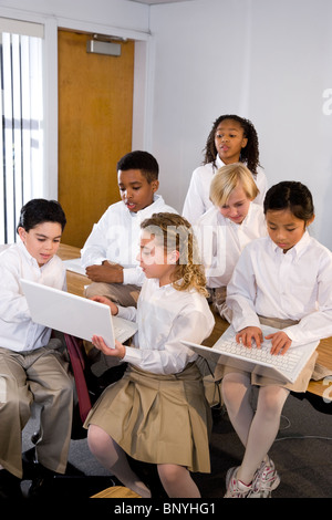 Diverse group of elementary school students in class using laptops Stock Photo