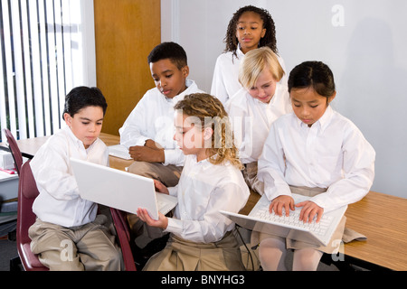 Diverse group of elementary school students in class using laptops Stock Photo