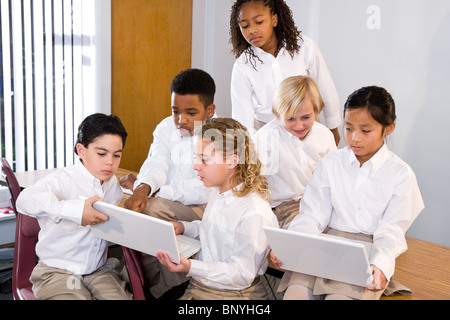 Diverse group of elementary school students in class using laptops Stock Photo
