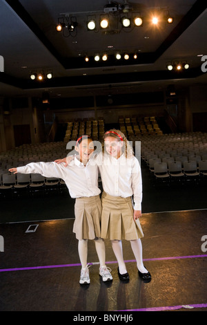Ten year old girls standing on auditorium stage in school Stock Photo