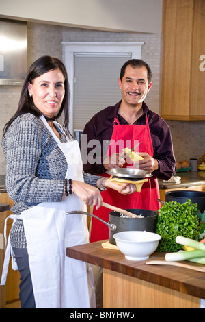 Mature Hispanic couple at home in kitchen preparing dinner Stock Photo