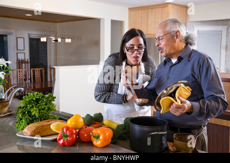 Senior Hispanic man and adult daughter cooking food in kitchen at home Stock Photo