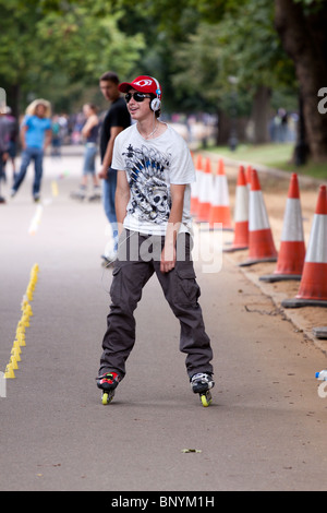 A male teenager enjoying himself with friends on a weekend using in line skates in hyde park, london Stock Photo