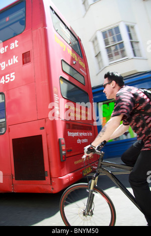 male cyclist following a bus on street in Brighton city centre Stock Photo
