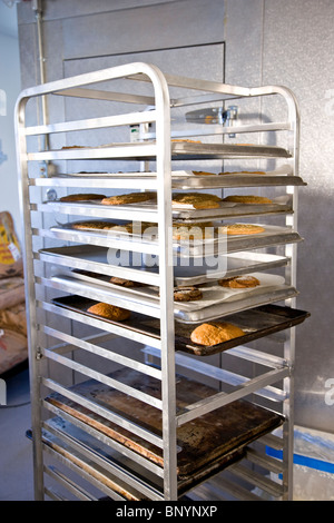 Baked goods cooling on racks in bakery Stock Photo