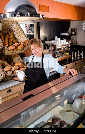 Waitress in restaurant standing behind counter Stock Photo