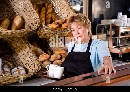 Waitress in restaurant standing behind counter Stock Photo