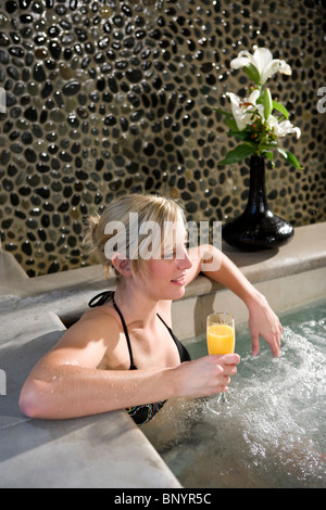 Young woman relaxing with drink in hot tub Stock Photo