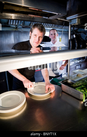 Chefs in commercial kitchen preparing dishes Stock Photo