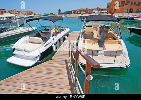 Two private motor boats moored to a wooden jetty in a tropical marina Stock Photo