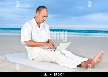Freelancer working on the tropical beach by laptop. Stock Photo