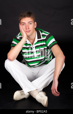 Portrait of a young man sitting on the floor. Stock Photo