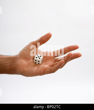 Man holding dice in hand with number five top side up Stock Photo