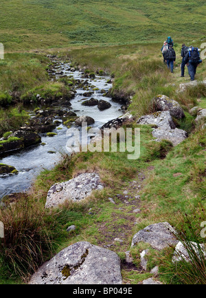 Hikers following path of river through Dartmoor National Park. Stock Photo