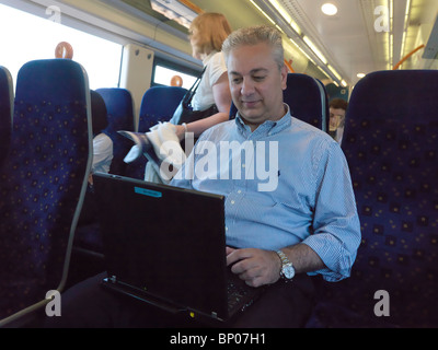 Businessman using a laptop on a train Stock Photo