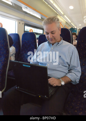Businessman using a laptop on a train Stock Photo