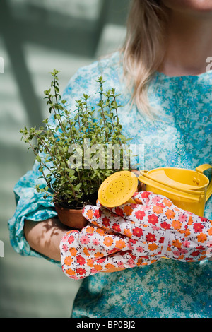 Woman holding watering can and plant Stock Photo
