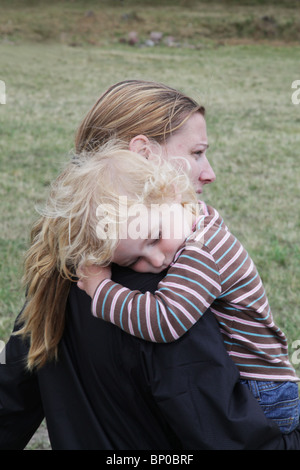 Tired toddler baby being carried sleeping resting on her mum's shoulder outdoors Stock Photo