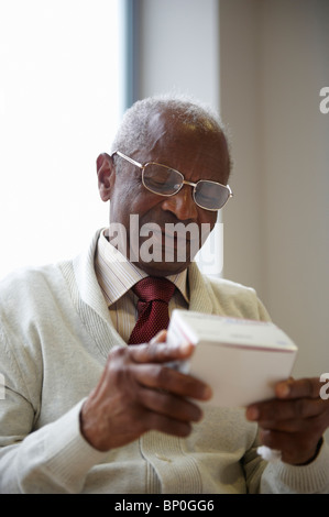 Elderly black man reading medicine box Stock Photo