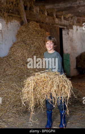 Boy with hay on fork, smiling Boy with hay on fork, smiling