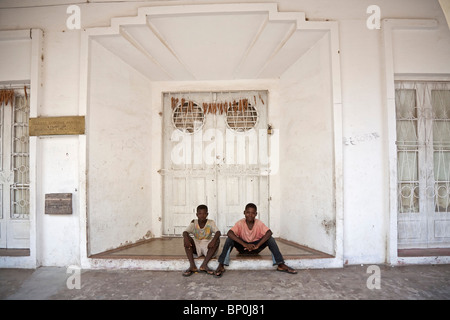 Mozambique, Ihla de Moçambique, Stone Town. Two boys sit on the step of a once-grand doorway in Stone Town. Stock Photo