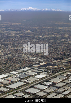 aerial view above Los Angeles warehouses across LA basin smog to snow covered San Gabriel mountains California Stock Photo