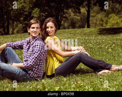 License available at MaximImages.com - Young happy smiling couple in their early thirties sitting on grass in a park Stock Photo
