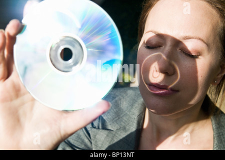 Woman holds DVD up to the sun Stock Photo