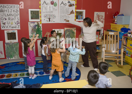 African American preschool teacher dancing with her students, Stock Photo