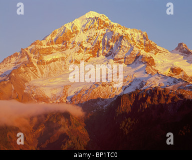 Sunset warms fresh snow on west side of Mt. Hood and wisps of fog, Mt. Hood Wilderness, Mt. Hood National Forest, Oregon, USA Stock Photo