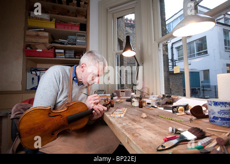 A classical violin restorer working on an instrument in his workshop, London, UK. Photo:Jeff Gilbert Stock Photo